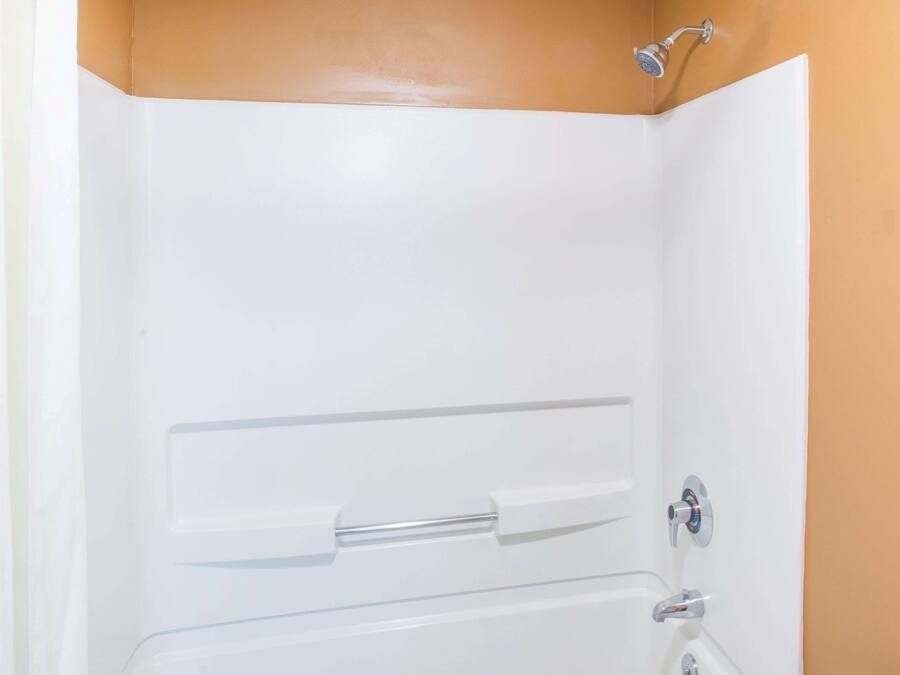 Eine weiße Badewanne mit Duschkopf, Handtuchhalter und Wasserhahn.