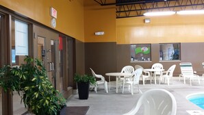 A hotel lobby with a pool area, including a reception desk, seating area, and a large potted plant. - Super 8 by Wyndham Plattsburgh (Plattsburgh)
