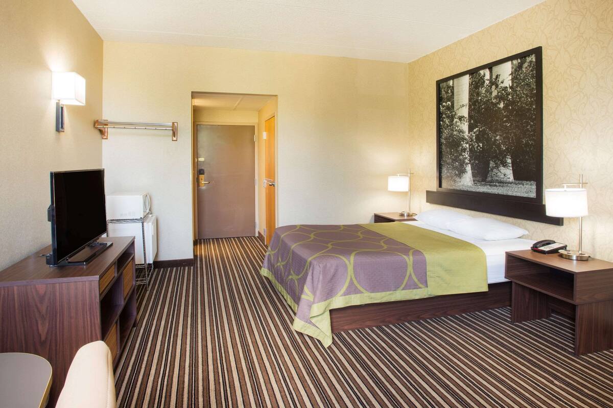 A hotel room with a bed, a television, a desk, and a chair.