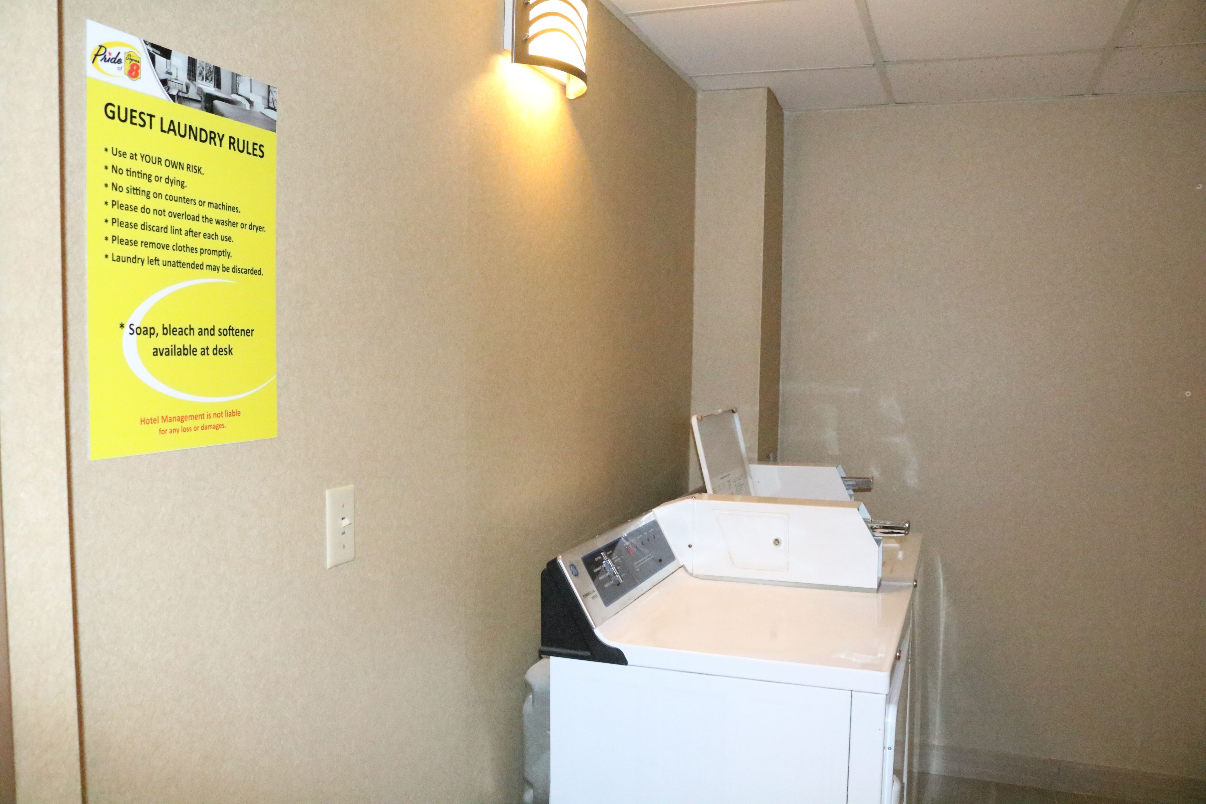 A laundry area with a sign detailing guest laundry rules, a washing machine, and a dryer.