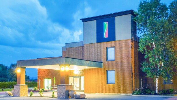A modern hotel with a flat roof, a covered entrance, and a prominent logo on the side. - Super 8 by Wyndham Plattsburgh (Plattsburgh)