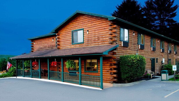 A log cabin-style building with a porch, windows, and a green roof. - Super 8 by Wyndham Lake George/Warrensburg Area (Lake George)