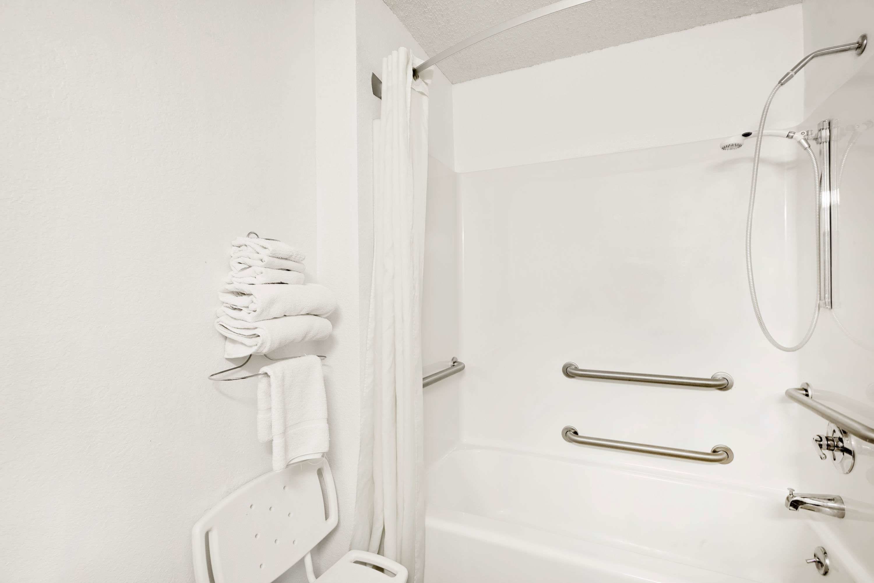 A bathroom with a shower, grab bars, and a towel rack.