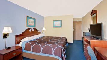 Habitación de hotel con cama, televisión, escritorio y dos lámparas de pared.