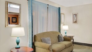 A hotel room with a sofa, two side tables with lamps, a mirror, and a curtain. - Super 8 by Wyndham Newburgh/West Point Near Stewart Airport (Newburgh)