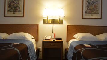 A hotel room with two beds, a nightstand with a lamp, a phone, and a remote control.