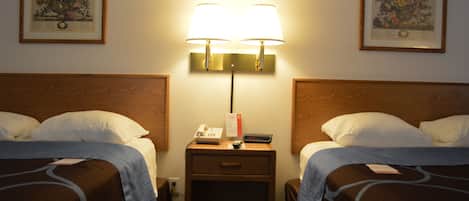 Habitación de hotel con dos camas, una mesita de noche con lámpara, teléfono y control remoto.