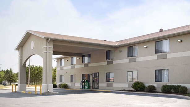 Un hotel moderno con entrada cubierta, varias ventanas y un área de estacionamiento.