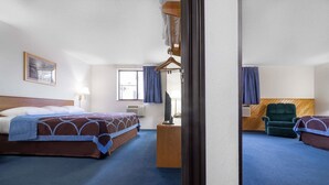 Habitación de hotel con una cama grande, un escritorio, una silla y un ventanal con cortinas.