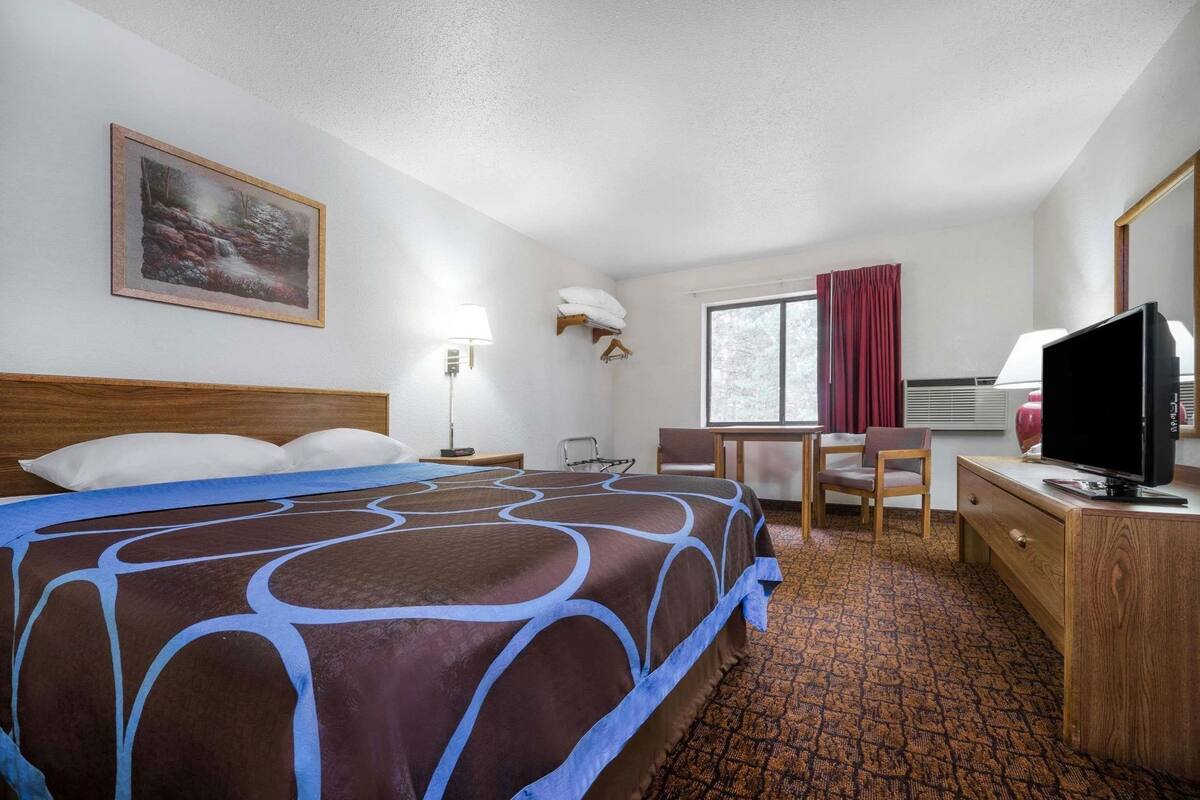 Une chambre d’hôtel comprenant un lit, un bureau, une chaise, une télévision et une fenêtre.