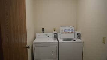 A laundry room with two stacked washers and dryers, a wooden door, and a white wall.