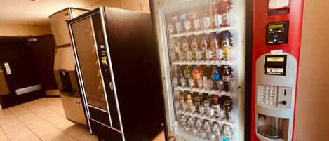 A vending machine stocked with various beverages and a refrigerator.