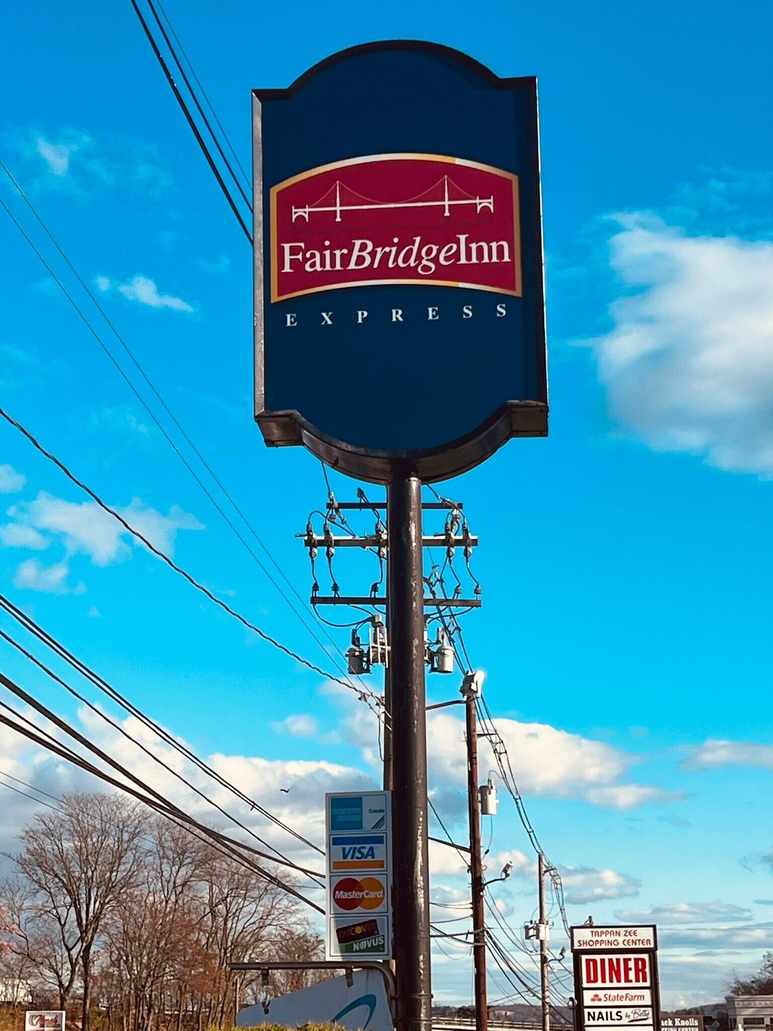A sign for FairBridge Inn Express with a clear view of the sky and power lines in the background.