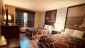 Une chambre d’hôtel avec deux lits, un bureau, une chaise et une grande fenêtre avec des rideaux.