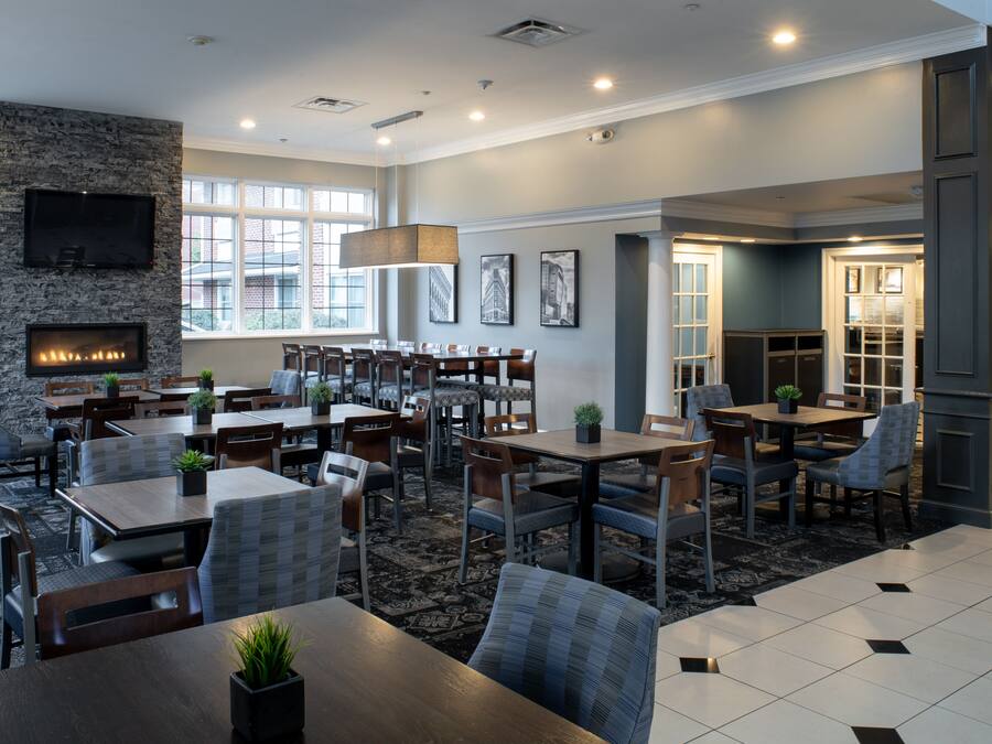 A hotel lobby with a fireplace, multiple seating areas, and a television mounted on the wall.