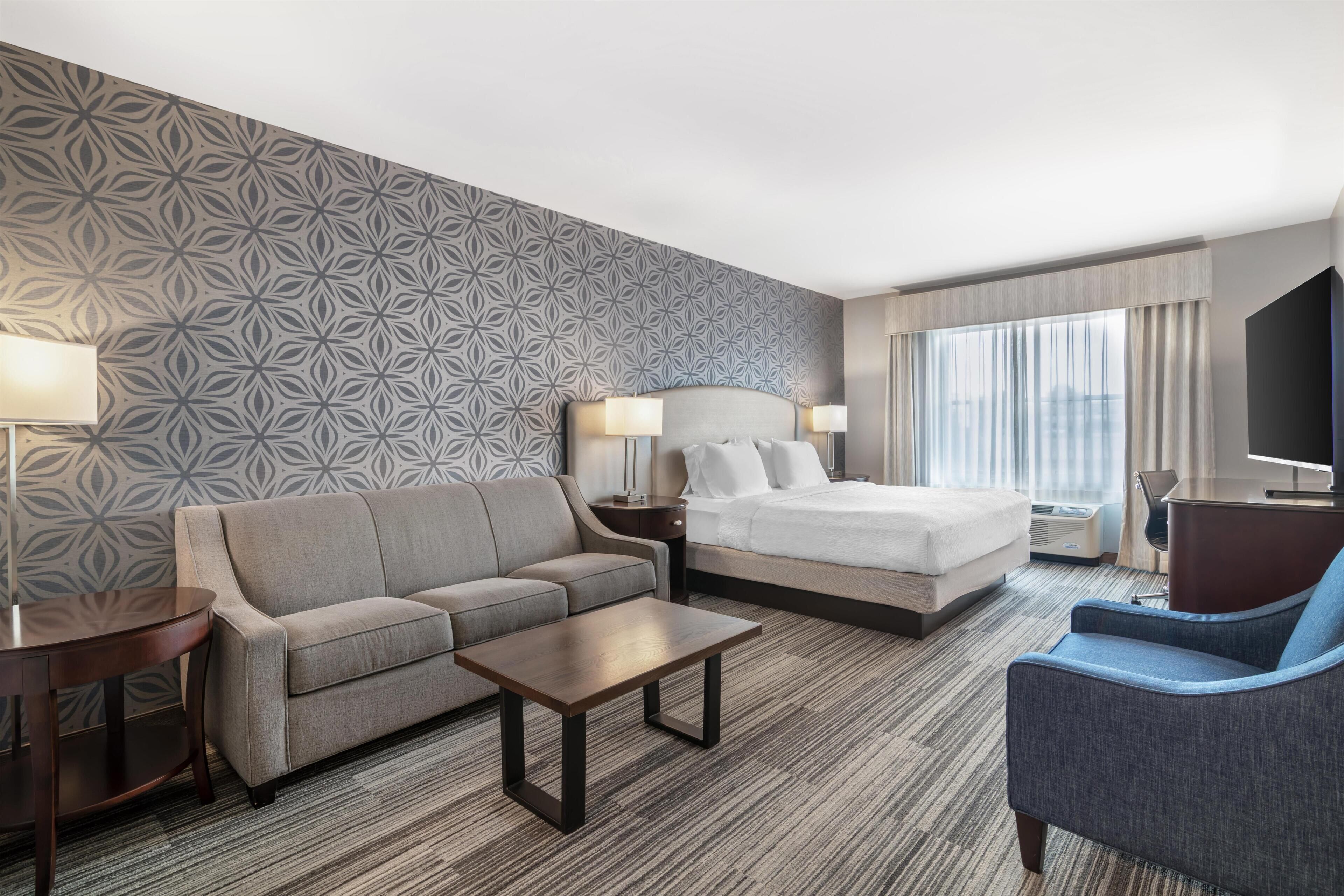 Une chambre d’hôtel équipée d’un canapé, d’un lit, d’un bureau, d’une chaise et d’un téléviseur.