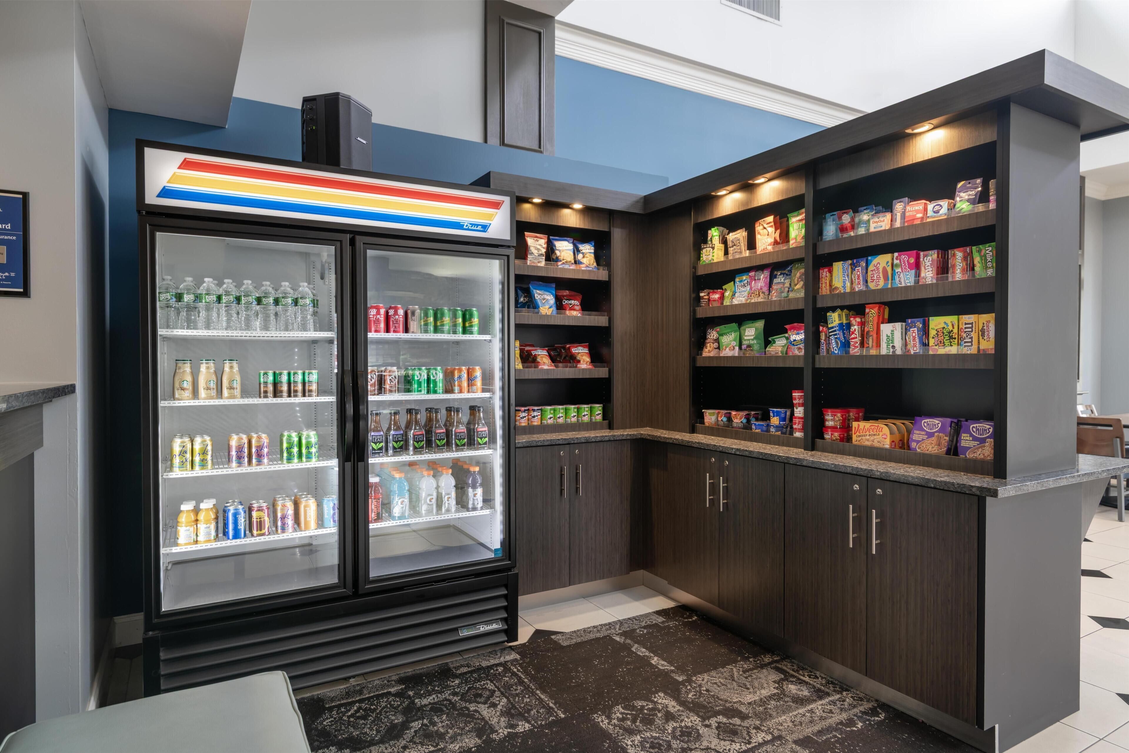 A self-service kiosk with a refrigerated beverage display and shelves stocked with snacks and packaged goods.