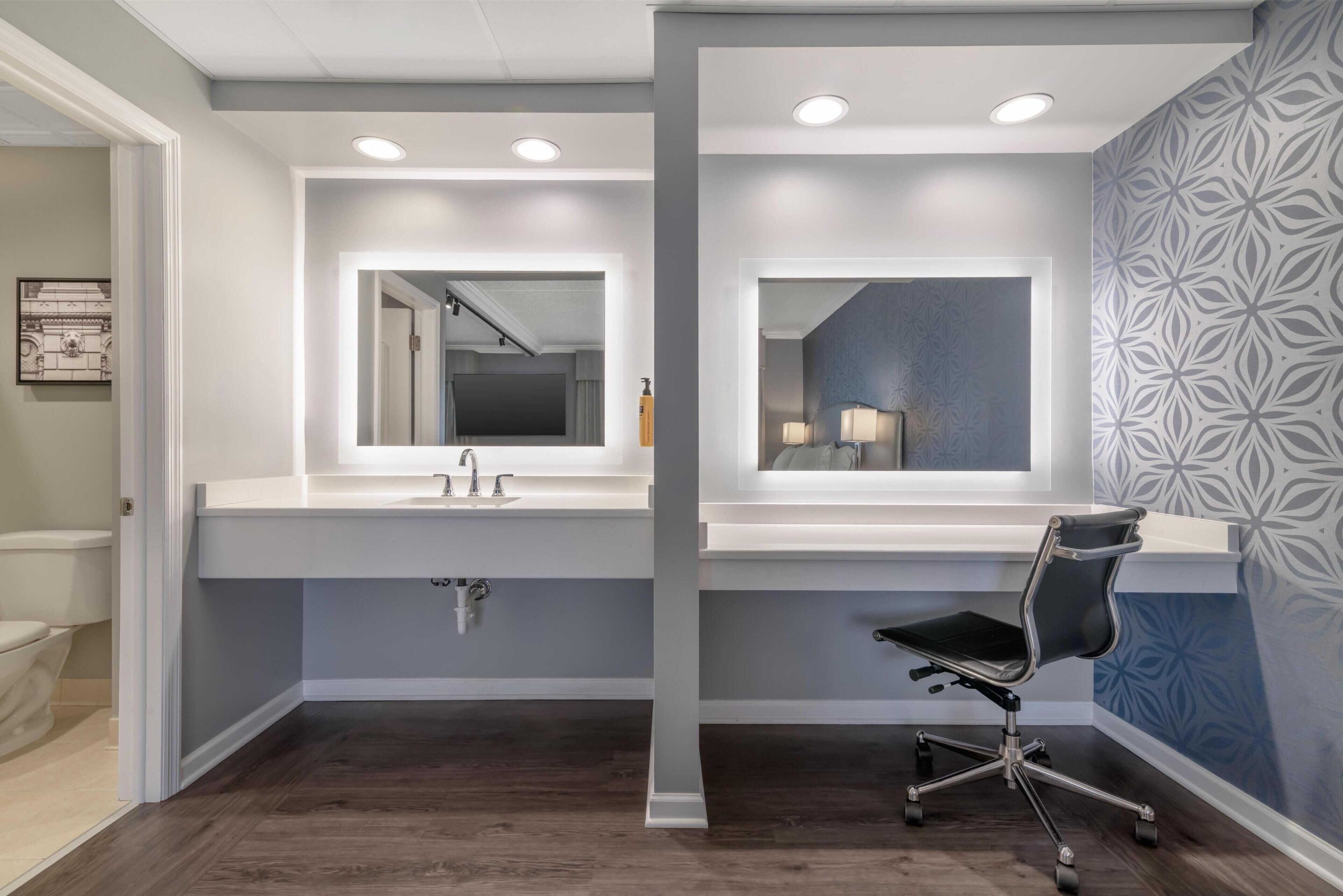 A modern bathroom with two sinks, a mirror, and a chair.