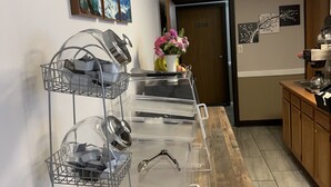 A kitchen area with a buffet setup, including a dish rack, a clear storage unit with compartments, and a coffee machine. - AmeriVu Inn (Park Falls)