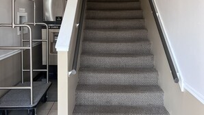 A carpeted staircase with a handrail, a wall-mounted mirror, and a painting above the stairs. - AmeriVu Inn (Park Falls)