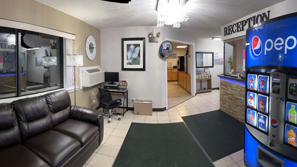 A reception area with a couch, a Pepsi vending machine, and a window with a view of a bar.