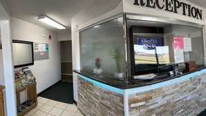 A reception area with a reception desk, a Pepsi refrigerator, a clock, a couch, and a computer desk.