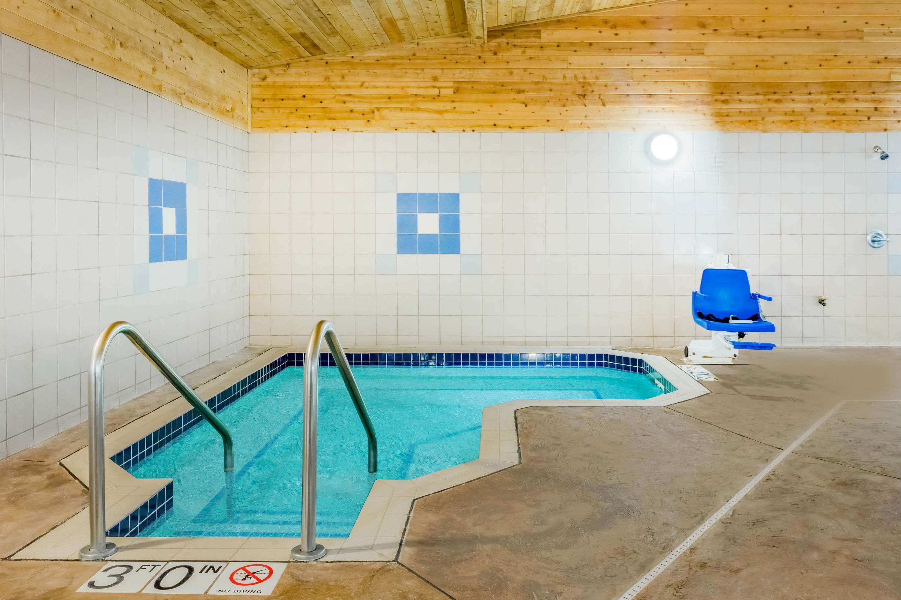 Una piscina interior pequeña con techo de madera y paredes de azulejos.