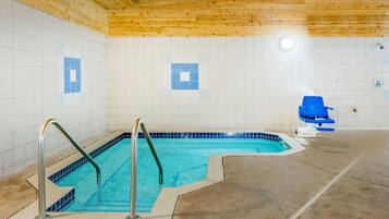 Una piscina interior pequeña con techo de madera y paredes de azulejos.
