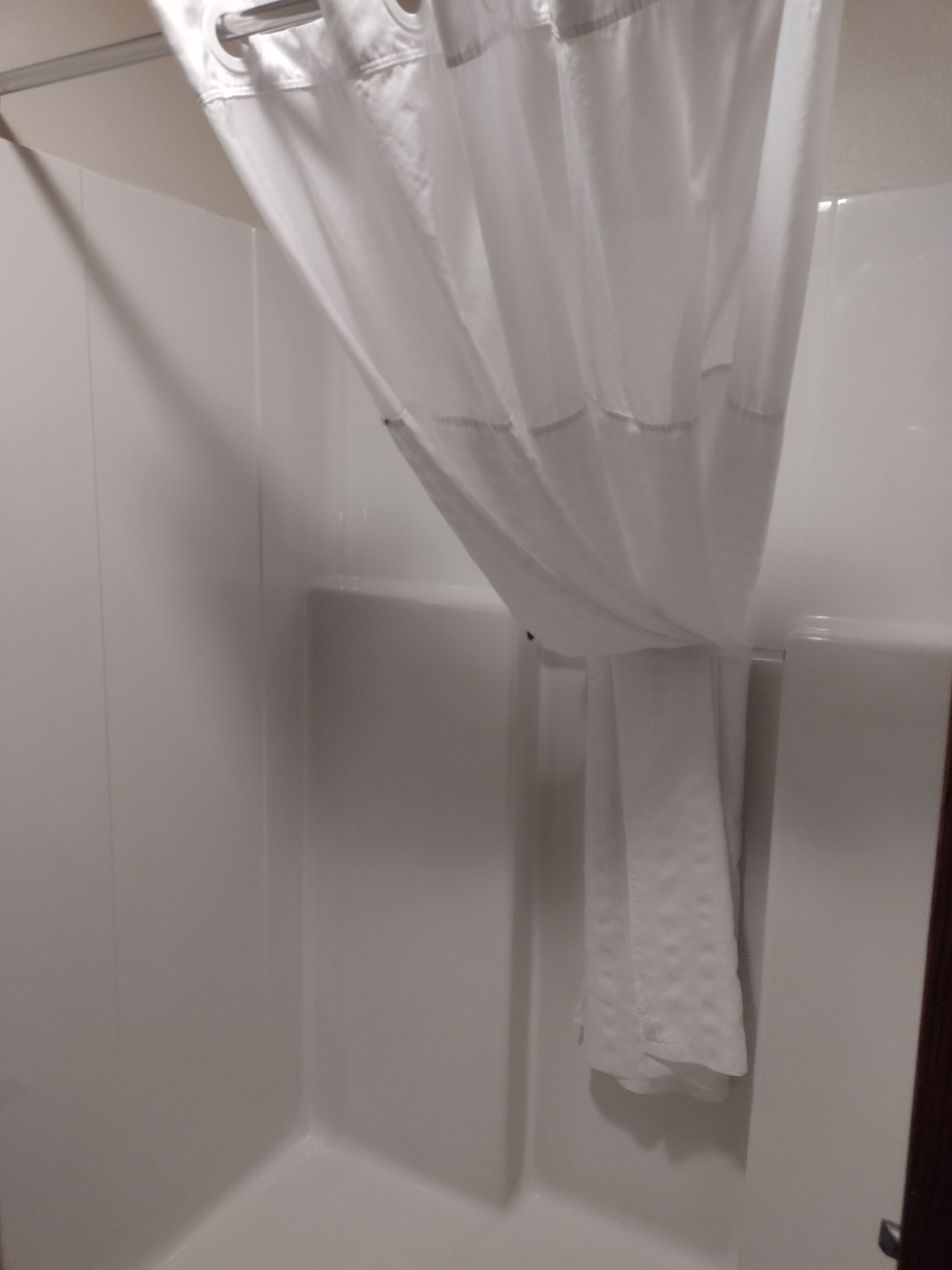 A bathroom with a shower curtain, a towel hanging on a rack, and a white tiled wall.