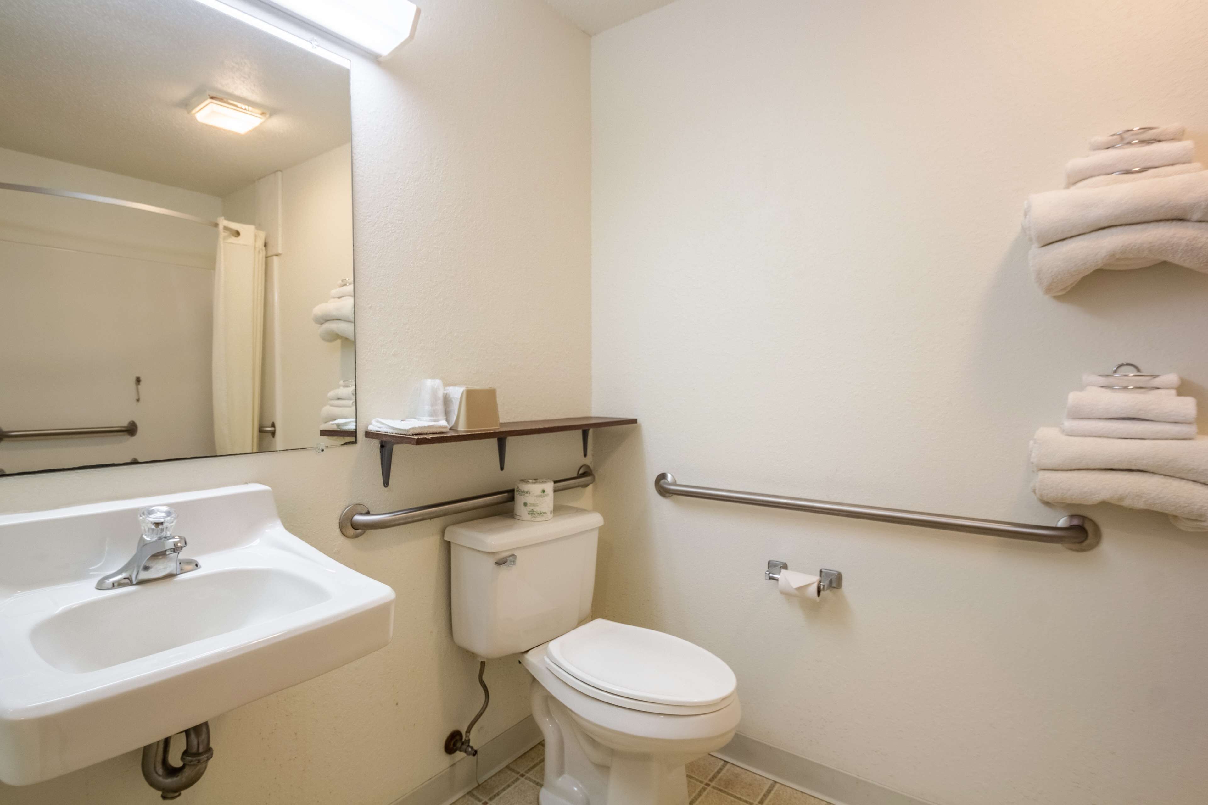 Un bagno con lavandino, WC e mancorrenti.