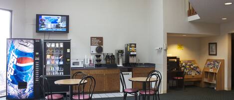 Un restaurante con una máquina expendedora, una máquina de café y un televisor montado en la pared.