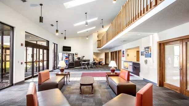 A spacious lobby with leather seating, a coffee station, and a TV mounted on the wall.