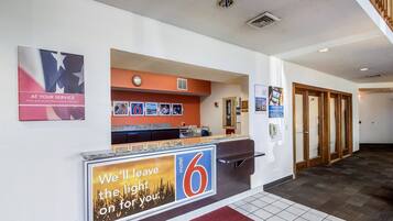 A hotel reception area with a counter, a clock, and a sign indicating a discount for active and retired military.