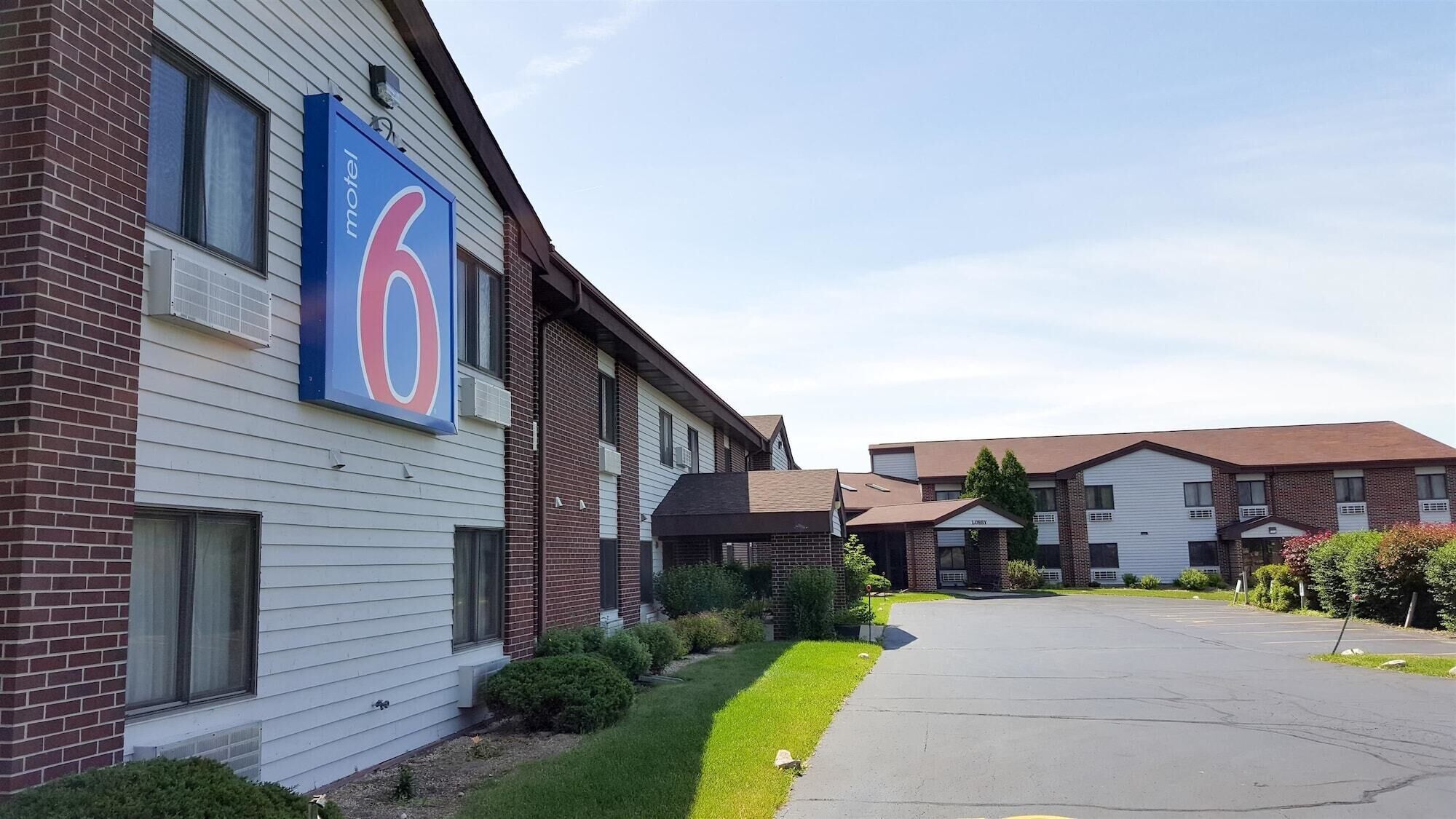 A motel with a large '6' sign, brick and siding exterior, and a parking lot.