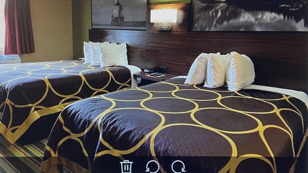 Habitación de hotel con dos camas, una mesita de noche, un televisor y una obra de arte en la pared.