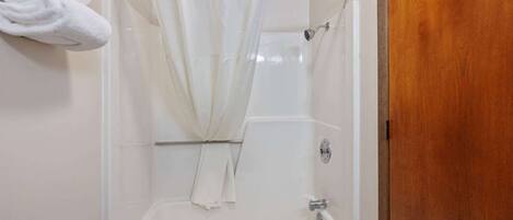 Un baño con ducha, bañera y toallero con toallas.