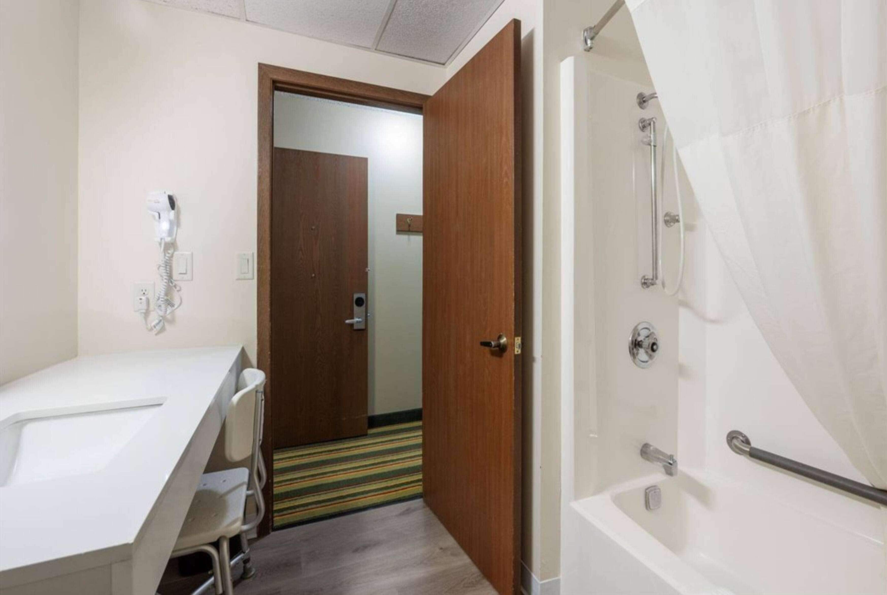 Un baño con ducha, lavamanos y una puerta que da a otra habitación.