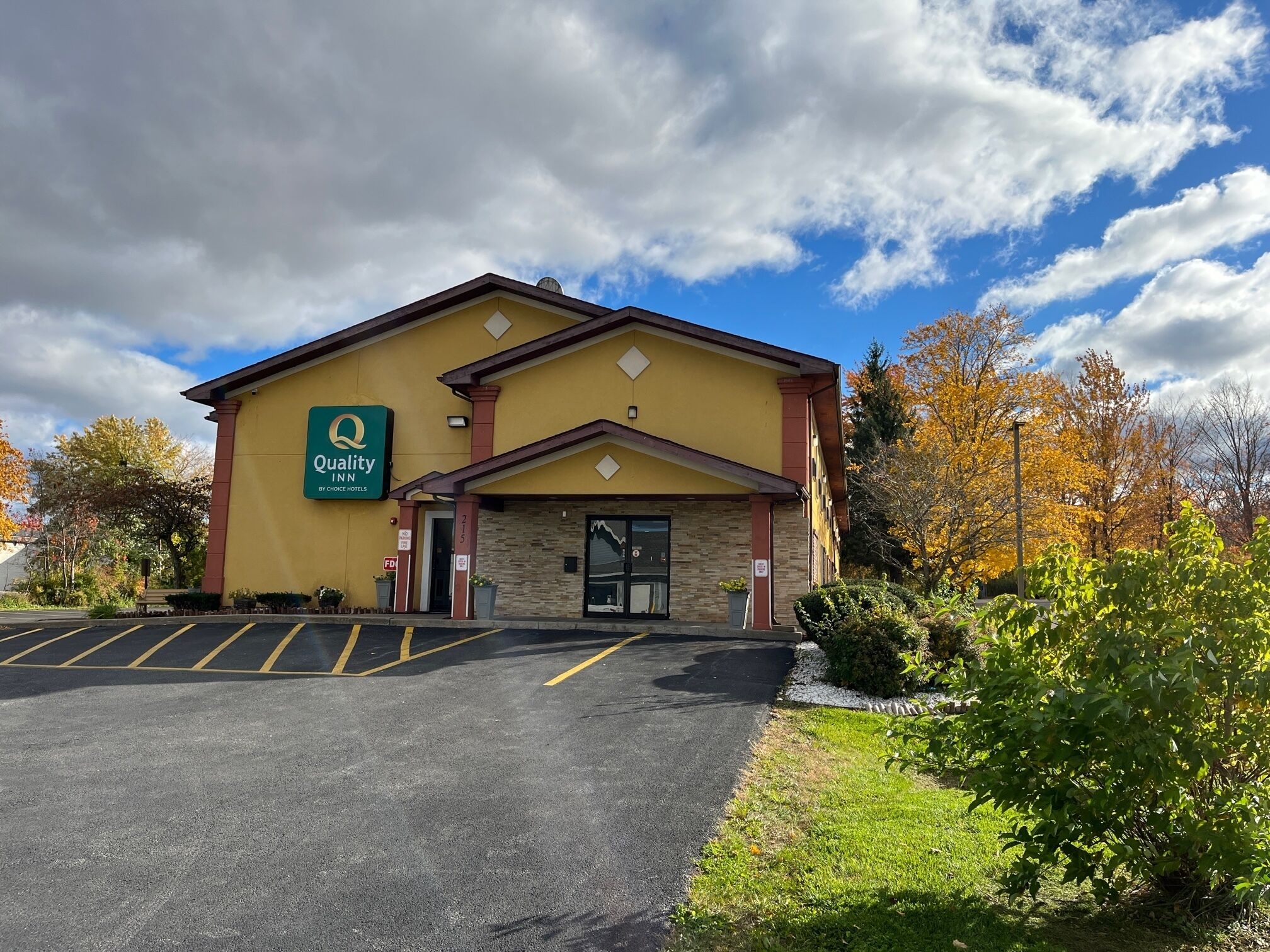 A Quality Inn by Choice Hotels building with a parking lot and autumn foliage.