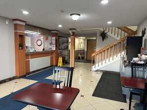 A hotel lobby with a reception desk, seating area, and a staircase.