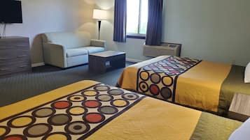A hotel room with two beds, a sofa, a coffee table, a TV, and a window with curtains.