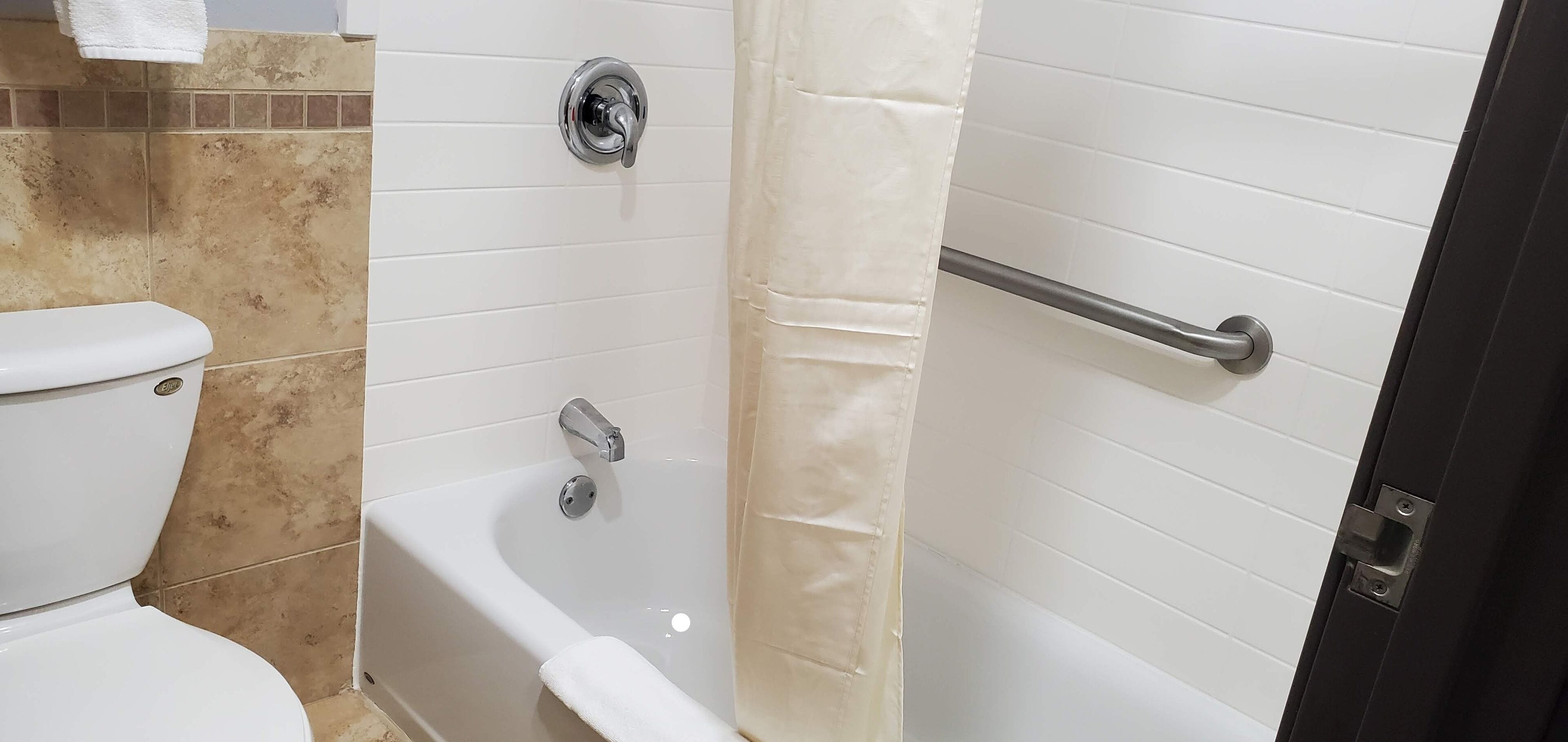 A bathroom with a toilet, bathtub, and shower curtain.