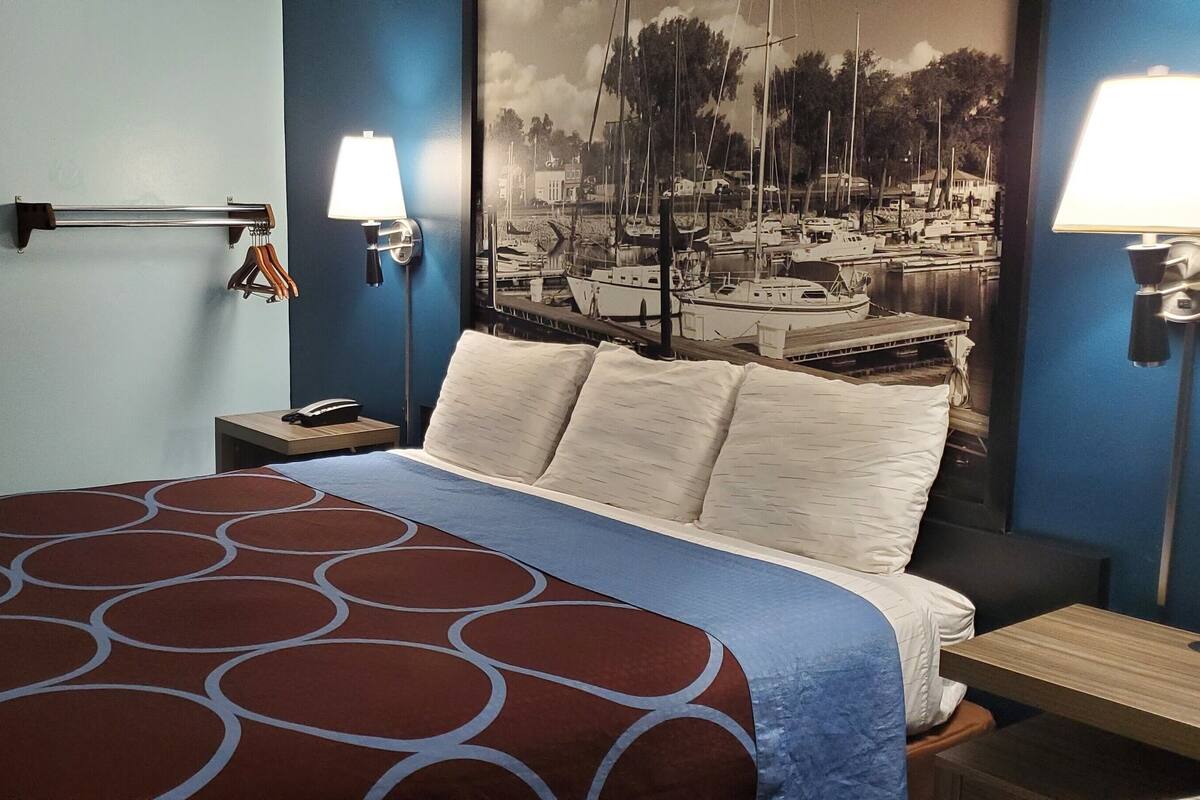 A hotel room with a bed, a nightstand, a lamp, and a wall-mounted towel rack.