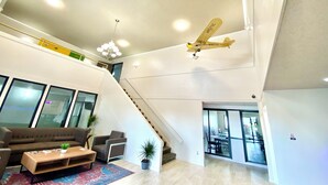 Un vaste espace de vie doté d’un haut plafond, d’un escalier et d’une maquette d’avion.
