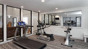 Une salle de sport à domicile équipée d’un tapis de course, d’un vélo elliptique et d’un vélo d’appartement.
