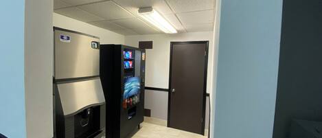 A hallway with vending machines, a trash bin, and a door.