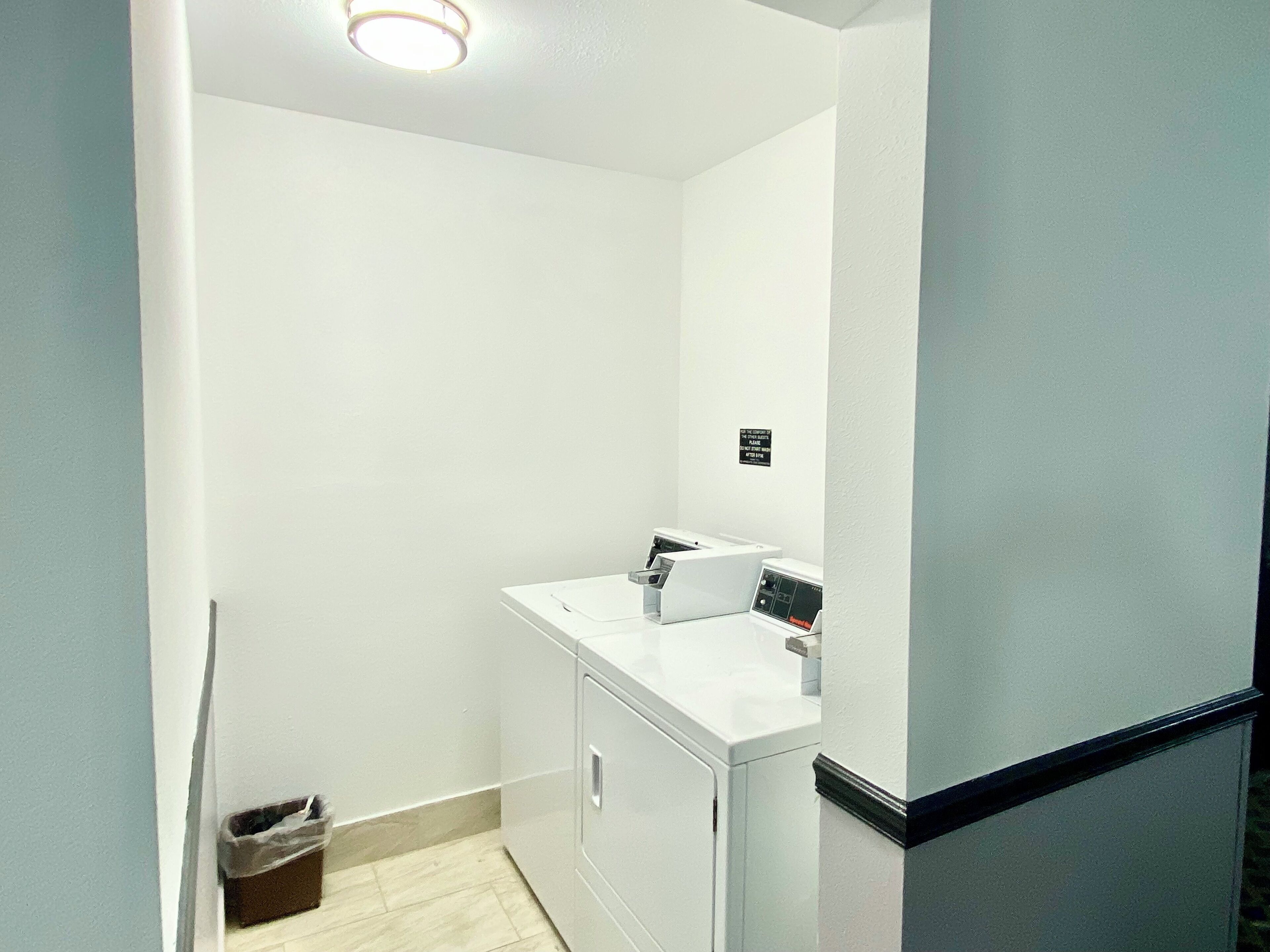 Une petite salle de bain propre, avec un lavabo blanc, un miroir et une poubelle.