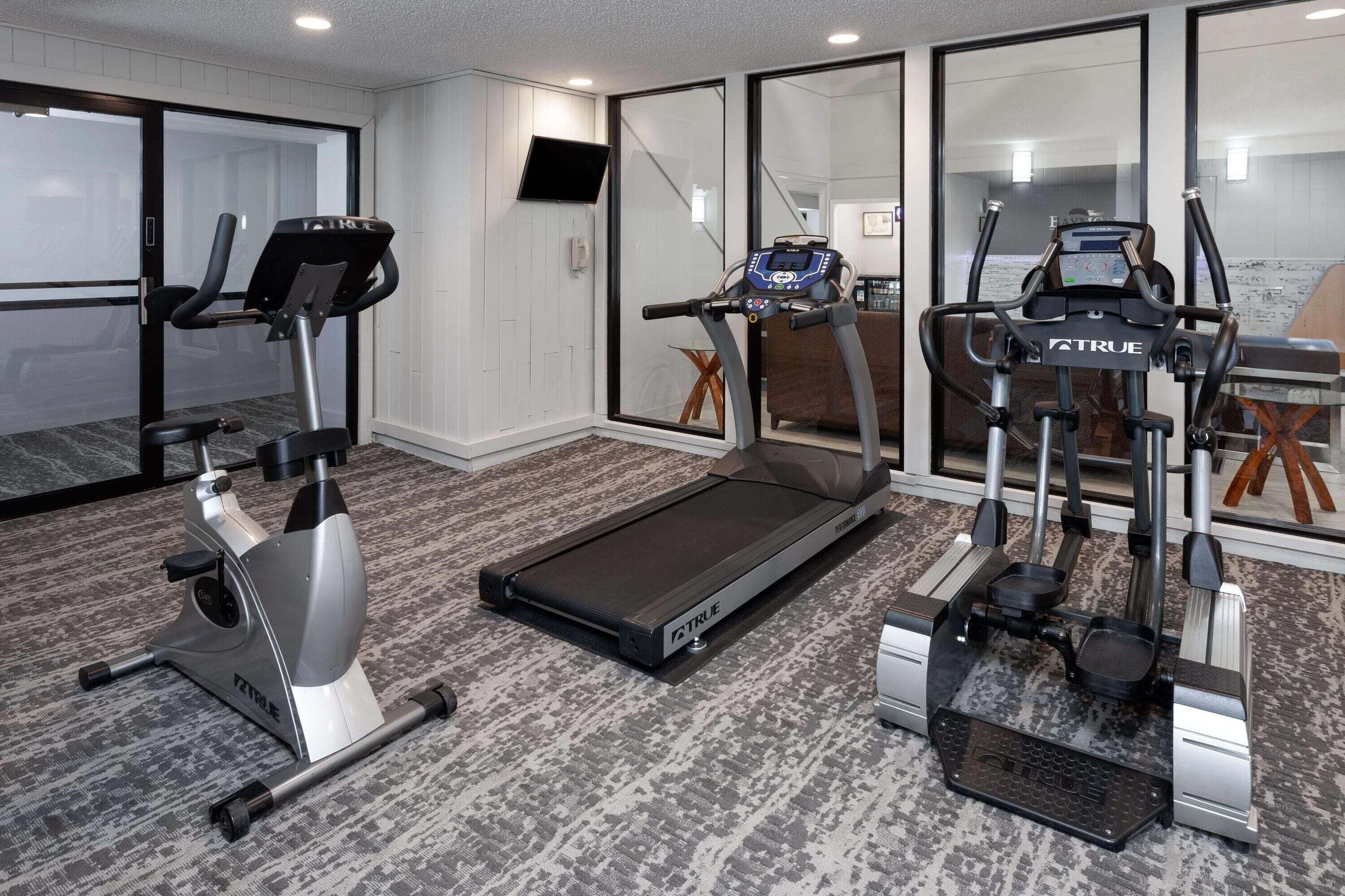 A home gym with a treadmill, elliptical, and stationary bike.