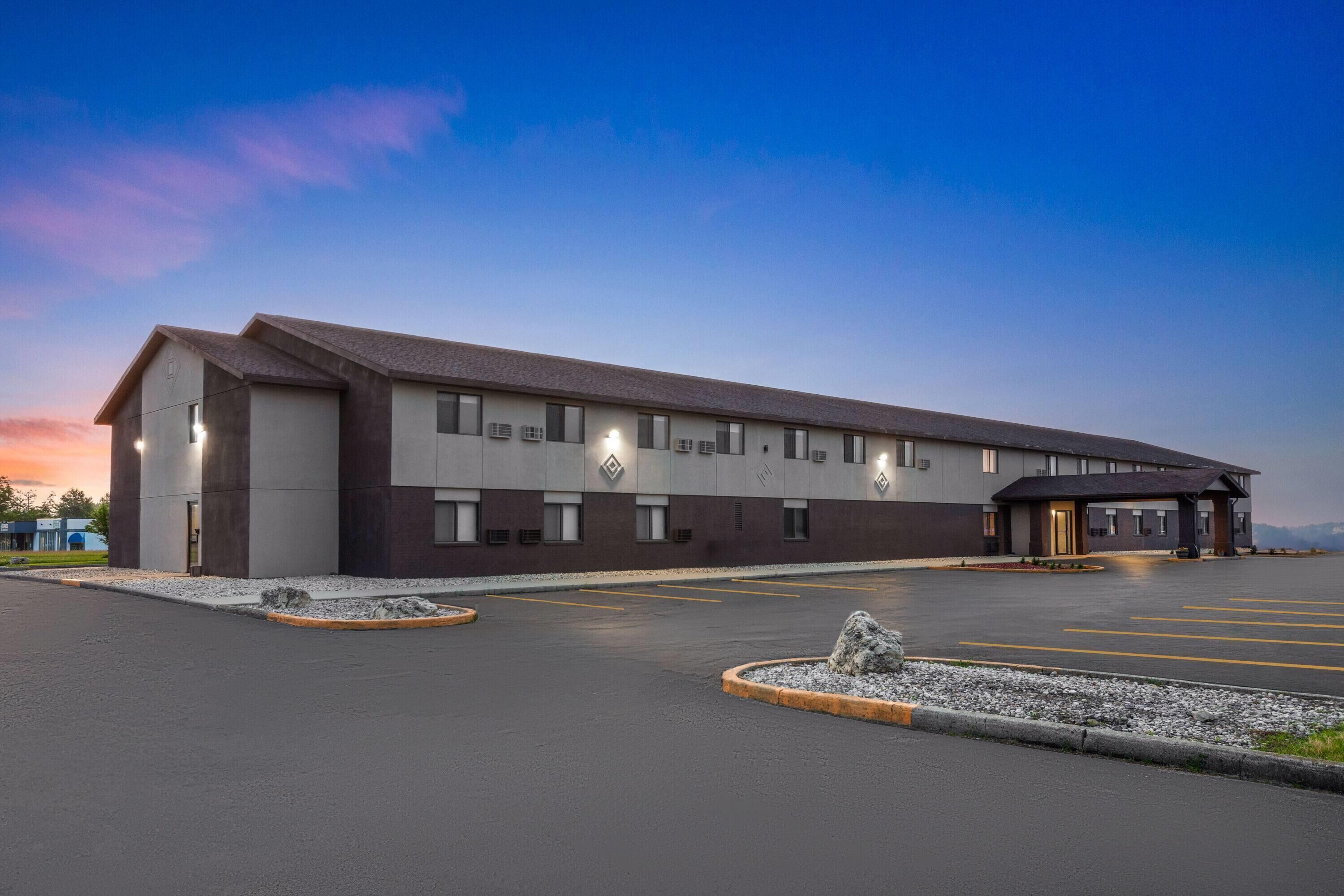 A modern building with a flat roof, large windows, and a parking lot with marked spaces.