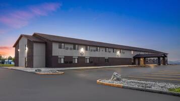 A modern building with a flat roof, large windows, and a parking lot with marked spaces.