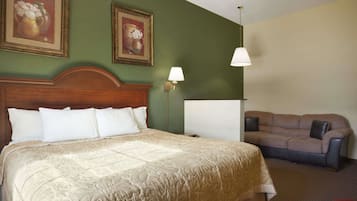 Une chambre d’hôtel avec un grand lit, un canapé et deux lampes fixées au mur.